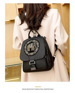 Detail of black woven texture backpack featuring a decorative metallic elephant emblem