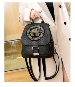 Detail of elephant embroidery and woven texture on a black faux leather backpack