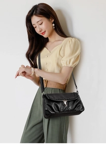 Détail du sac bandoulière rétro en cuir noir avec bordure tressée et fermoir en métal