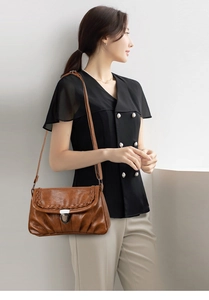Détail du sac à bandoulière vintage en cuir marron avec bords tressés et boucle argentée