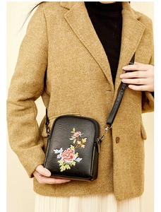 Detail of floral embroidery on a black faux leather crossbody phone bag for women