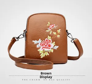 Close-up of ethnic floral embroidery and leather texture on a brown crossbody bag