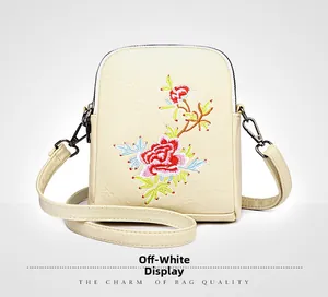 Detailed view of floral embroidery on cream white PU leather crossbody phone bag