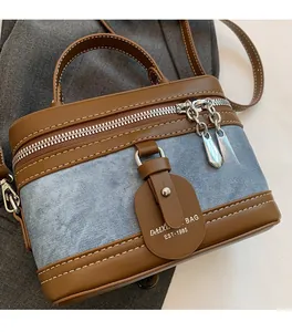 Detailed macro view of retro box bag with blue denim texture and brown leather trim