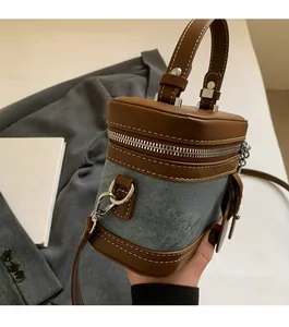 Detail of brown leather and blue denim patchwork box bag with silver zipper and handle