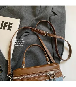 Detail view of contrast stitch box bag in brown leather and blue denim with dual zippers
