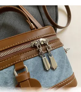 Detail of silver dual zippers and contrast stitching on denim leather box bag