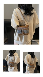 Detail view of two-tone brown and gray bucket bag with chain tag and leather strap
