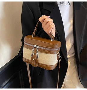 Detail of a chic plaid canvas and brown leather box bag with dual zippers and silver chain