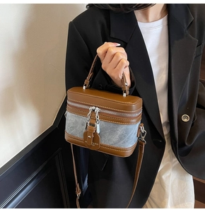 Detail of vintage box bag featuring brown leather and blue denim patchwork with dual zippers