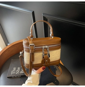 Detail of a brown leather and beige canvas box bag with silver hardware and top handle