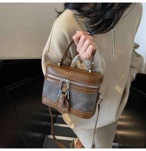 Modèle portant un sac bandoulière vintage en cuir marron et tissu gris de style boîte