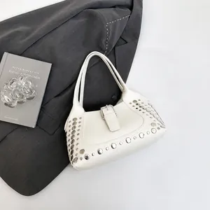 Dettaglio borsa in pelle martellata bianca con borchie argentate e fibbie in metallo