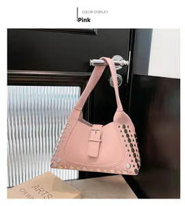 Dettaglio borsa a spalla in pelle rosa con borchie argentate appesa a una maniglia nera