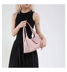 Dettaglio della borsa in pelle rosa con borchie argentate e fibbie in metallo stile Y2K
