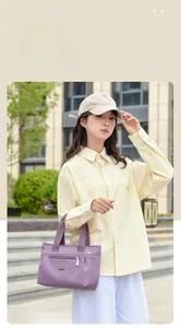 Dettaglio della borsa tote in nylon viola con manici larghi in un ambiente urbano