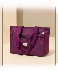 Dettaglio borsa tote in nylon bordeaux con finitura testurizzata e scomparti con zip