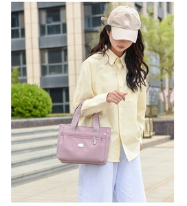Dettaglio della borsa tote in nylon lavanda con tasca con zip e logo in metallo lucido