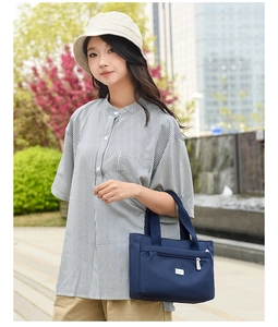 Dettaglio della borsa tote in nylon blu navy con tasca frontale indossata dal modello