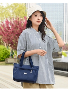 Dettaglio della zip argentata e placca logo sulla borsa a spalla in nylon blu scuro