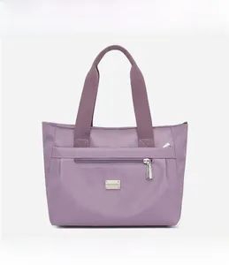 Dettaglio borsa tote in nylon viola con tasca frontale a zip e logo metallico lucido
