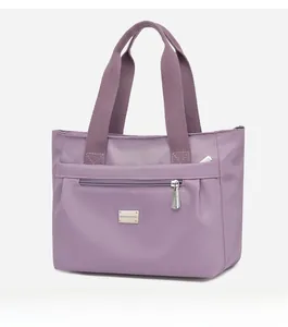 Dettaglio della borsa tote in nylon viola con tasca frontale con zip e logo del marchio