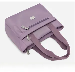 Dettaglio della borsa tote in nylon lilla con tasca frontale e trama della tracolla