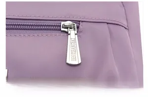 Dettaglio ravvicinato della cerniera in metallo argento su borsa a tracolla in nylon viola