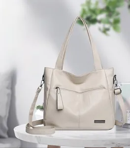 Detailed texture of off-white lychee grain leather tote bag with metallic zipper and logo