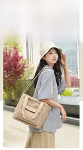 Outdoor lifestyle shot of a large beige nylon shoulder bag with functional pockets