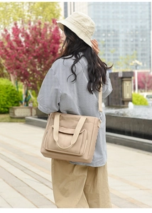 Detail of khaki nylon tote bag with front pocket and adjustable strap in outdoor setting