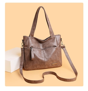 Detail of vintage brown tote bag with metal brand plaque and practical front zip pocket