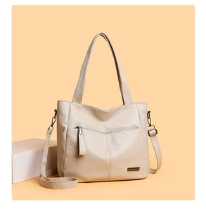 Detail view of cream tote bag with metal BaileTao logo and adjustable shoulder strap