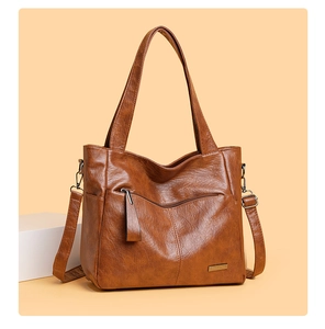 Detailed view of brown tote bag with metal zipper and adjustable leather strap