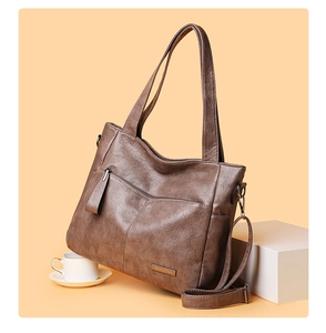 Detailed close-up of dark brown leather tote bag texture with metal logo and side hook