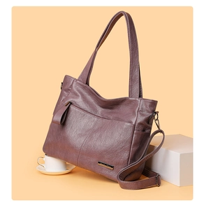 Detail view of the soft textured purple faux leather tote with metallic logo and wide strap