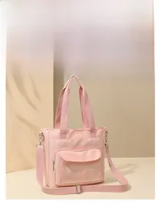 Detail of pink nylon tote bag showing front zipper pocket and adjustable strap texture
