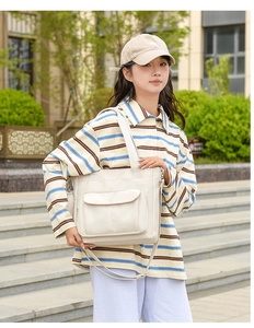 Outdoor shot of beige nylon tote bag featuring front flap pocket and adjustable strap