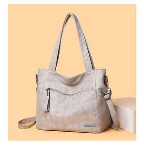 Detail of the gray tote bag showing pebble leather texture and metal brand tag