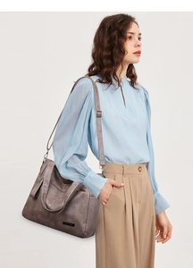 Detail of grey-brown tote bag featuring high-quality leather texture and metallic logo