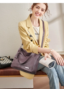 Detail view of purple leather tote bag with metal accent and adjustable strap shown on model