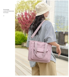 Pink nylon shoulder bag detail showing front pocket and multiple storage compartments