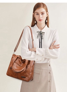 Close-up of caramel brown tote bag with metal logo and adjustable shoulder strap