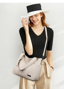Detail of cream tote bag in lychee texture with dual wide handles and brand plate