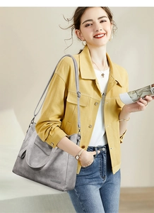 Close-up of grey leather tote bag on model showing adjustable strap and large capacity
