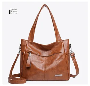 Macro detail of yellow-brown tote bag featuring litchi grain PU leather and silver logo