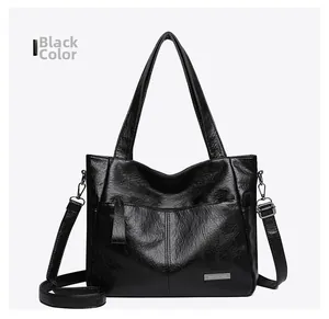 Close-up of black litchi grain leather tote bag with zipper detail and adjustable strap