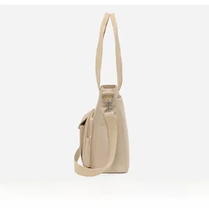 Side view of beige nylon tote bag with reinforced handles and adjustable shoulder strap