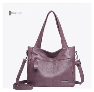 Detail of purple tote bag showing grainy texture, zipper pocket, and metallic logo