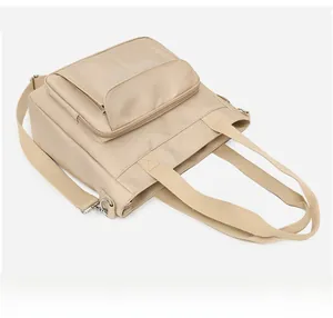 Detailed view of beige nylon tote bag with front zipper pocket and adjustable strap